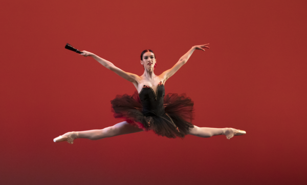 A dancer in black tutu does split jump