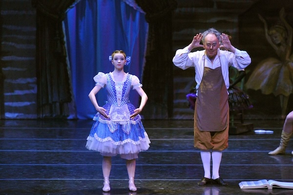 A doll-like dancer stands next to the toymaker