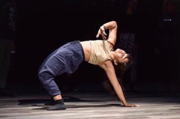 A dancer in purple pants bends backwards