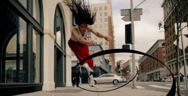 A dancer in red leaps on a city street
