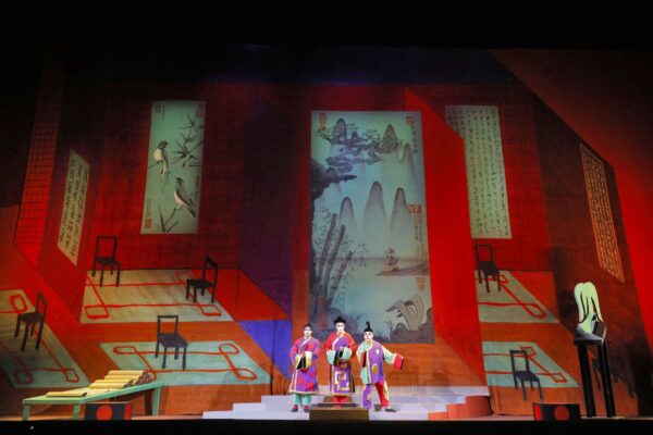 Three figures in room with Asian decor from LA Opera's Turandot, featuring a set designed David Hockney