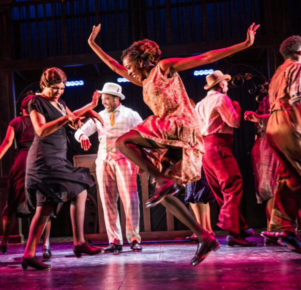 A dancer leaps in front of a group