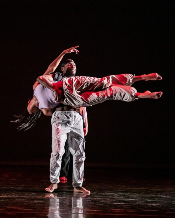 A dancer holds another dancer perpendicular