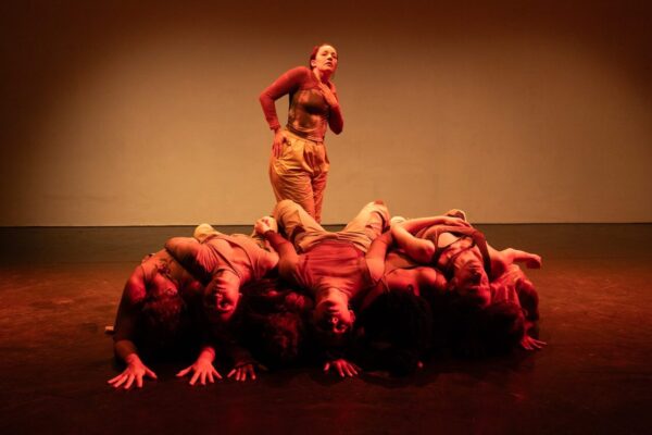 A solo dancer emerges above a group