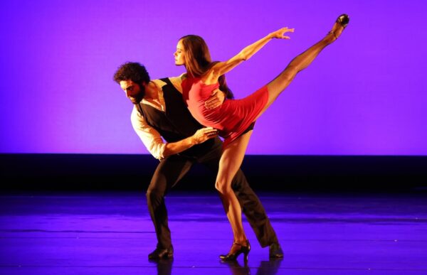 A dancer in red is held by her partner