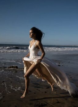 Model in wedding gown on beach sand