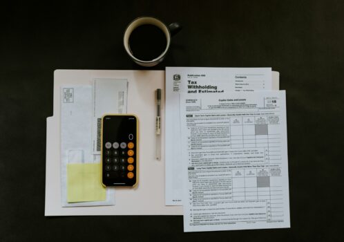Calculator on top of financial documents on black background.