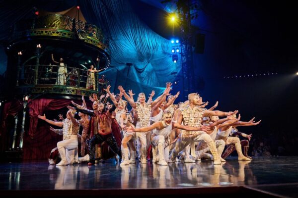 A crowd of performers in gold and silver