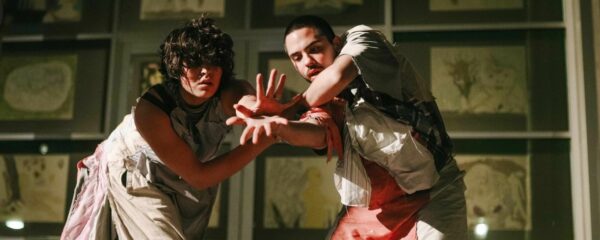 Two dancers intertwine hands