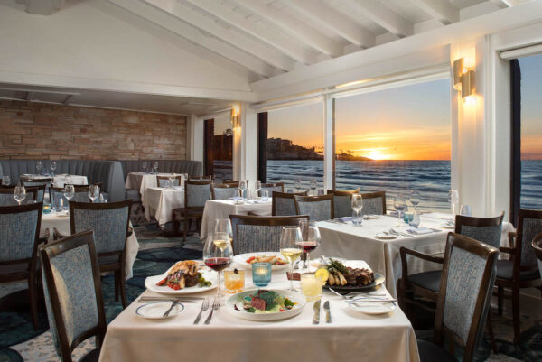 The dining room of the Marine Room showing tables before an ocean view.