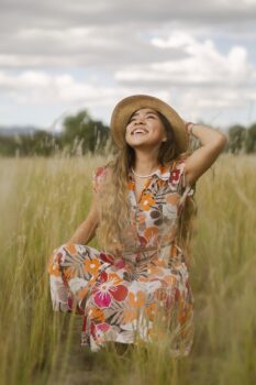 Woman wearing hat smiling in a field.