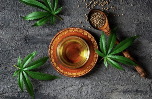 Top view of green kratom in bowl with spoon next to it.