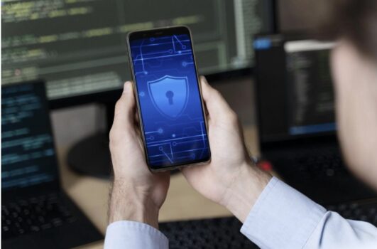 Person holding smartphone with security icon on screen.