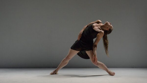 A dancer in a black dress bends backwards
