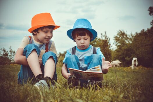 Two boys reading a book in the park.