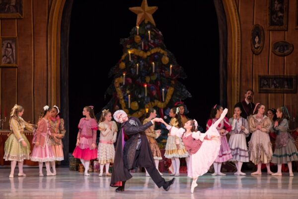 People dance in front of Christmas tree
