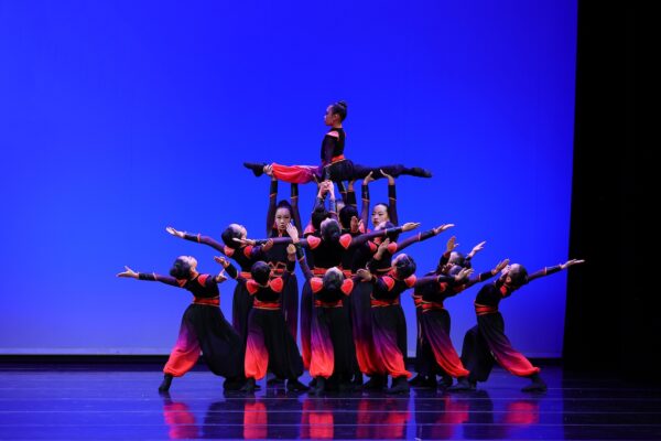A group of dancers lift another dancer in the splits