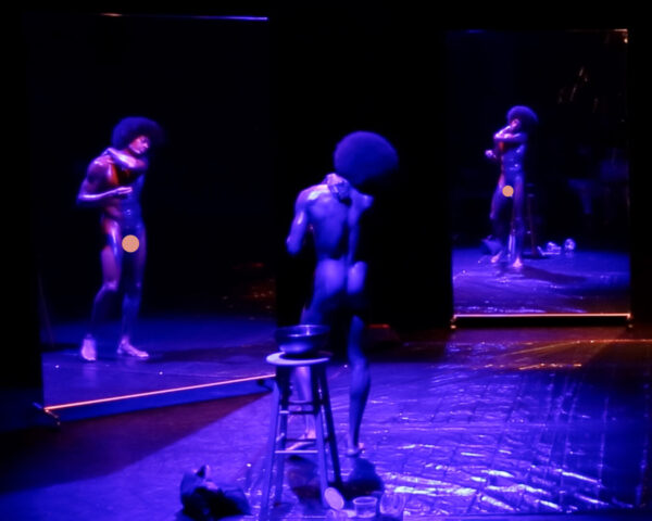 A nude man looks at mirror