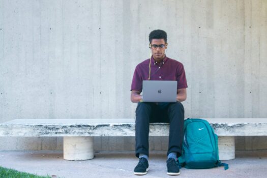 Man writing research paper on park bench.