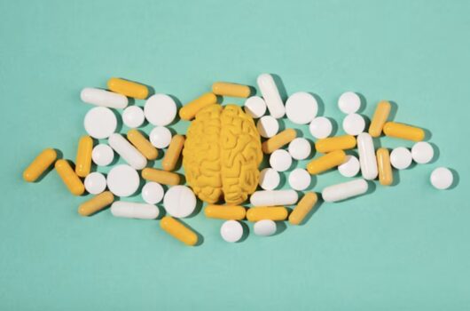 Various pills scattered around figure of yellow brain.