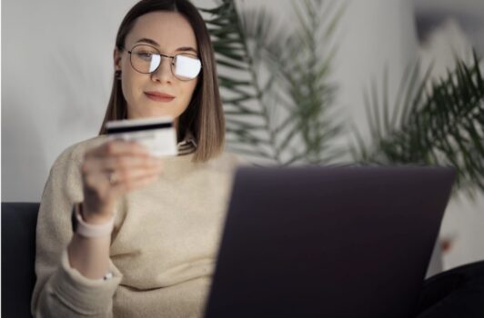 Woman making payment with card at laptop.