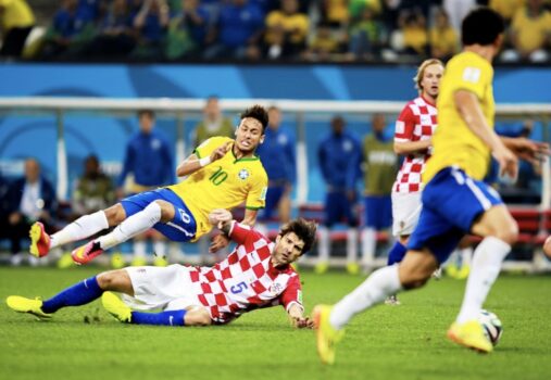 Soccer players colliding on field.