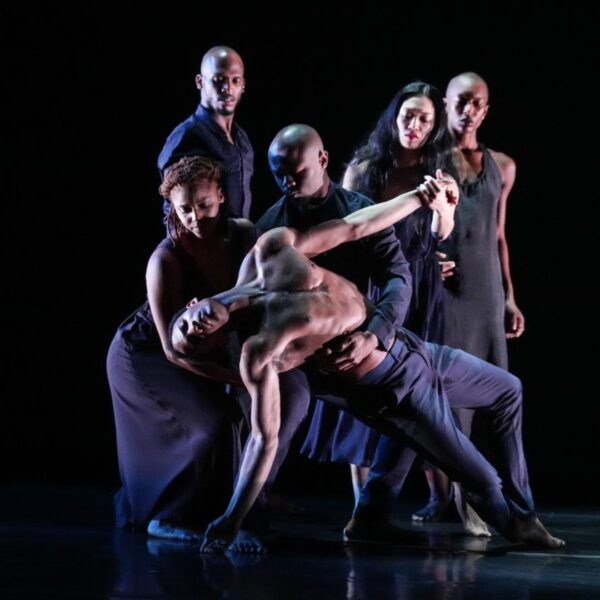 A group in black hold up a male dancer