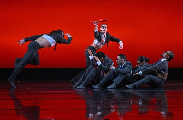Dancers in suits against red backdrop
