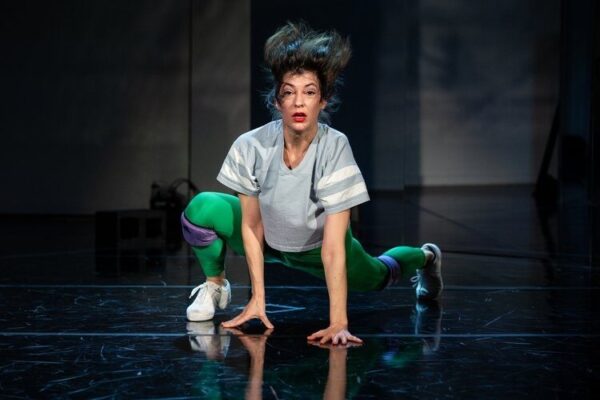 A dancer in green lunges