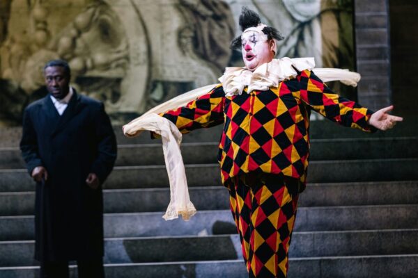 A clown with his arms open wide in Rigoletto