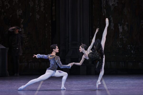A dancer holds another with her leg straight up