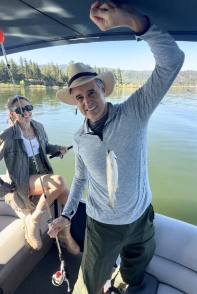 A man holding up a small fish in a boat.