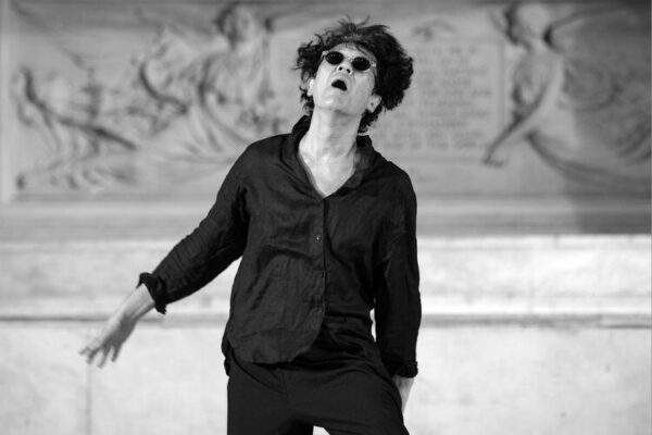 A dancer in sunglasses faces the camera