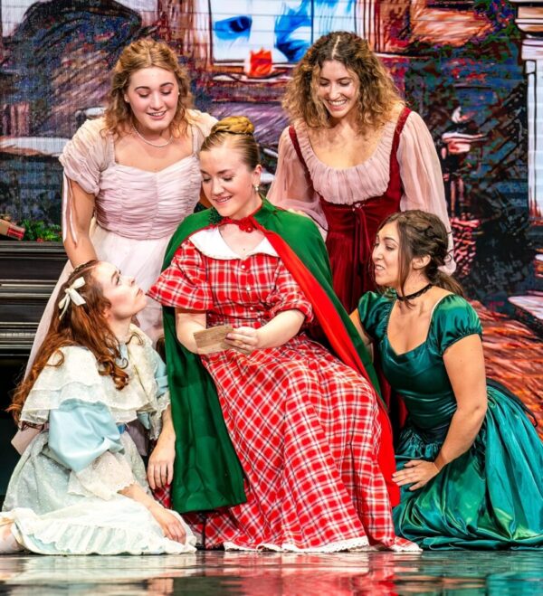 A woman in red sits surrounded by four young women in Little Women Ballet