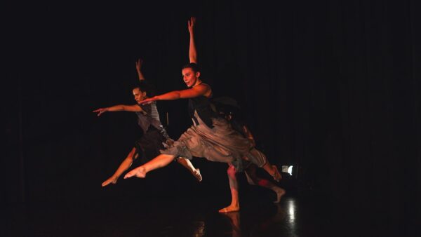 Dancers kick in dark lighting
