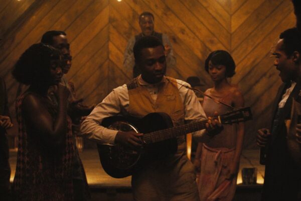 screenshot from Sinners. a black man plays the guitar.
