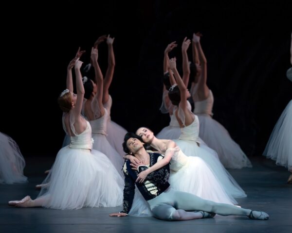 A dancer embraces man on ground in Giselle