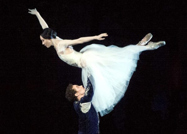 A dancer lifts his partner in the air in Giselle