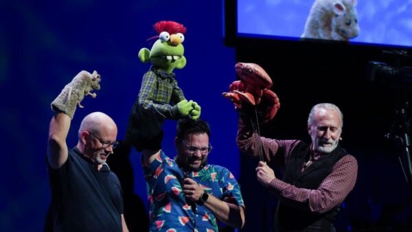 Three men hold puppets aloft