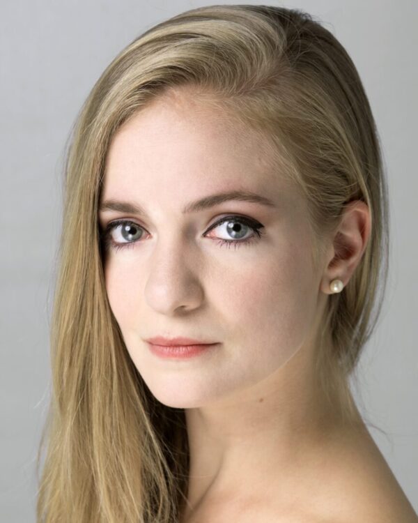 A blond woman looks at the camera