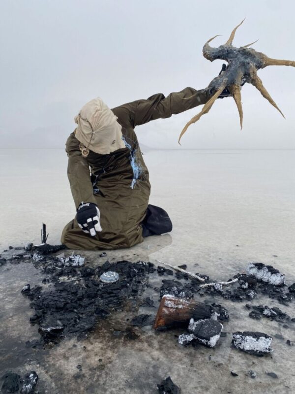 A masked figure on the beach