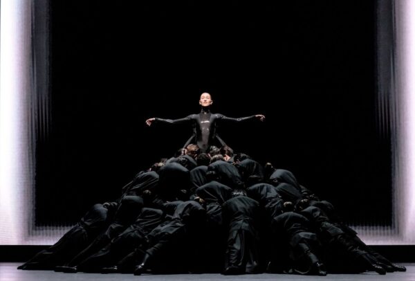 A figure atop figures in black