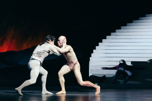 Two dancers struggle in front of staircase