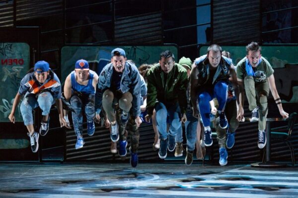 a group of dancers jump in West Side Story