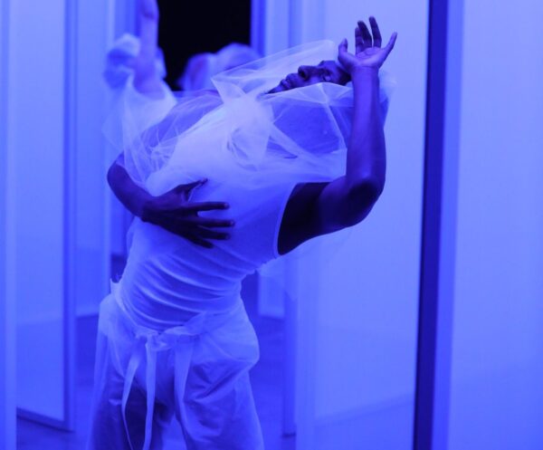 A dancer in white bends back