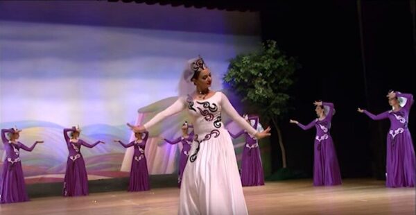 A dancer in white with dancers behind her