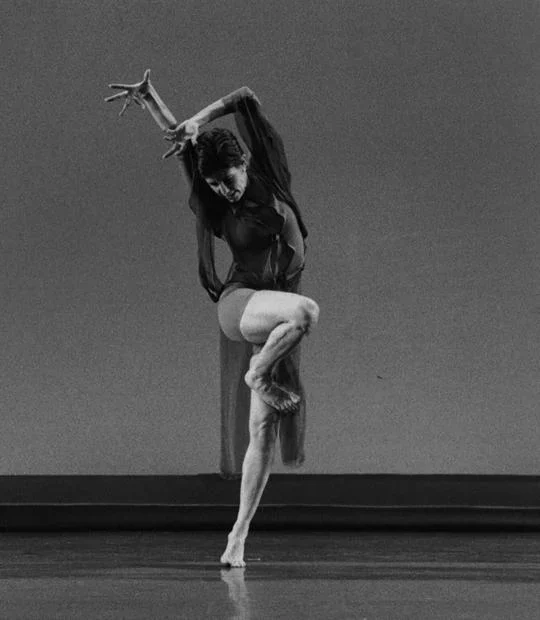 A dancer in dark lifts her leg