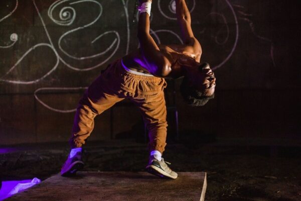 A dancer in brown pants bends backward