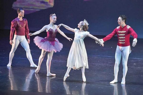 Four dancers in different costumes in a line