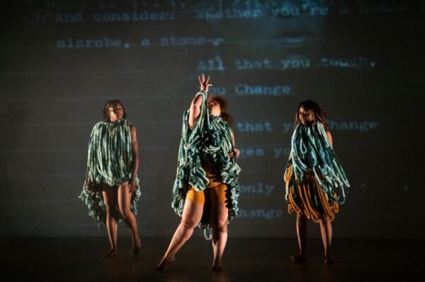 Three dancers in front of writing